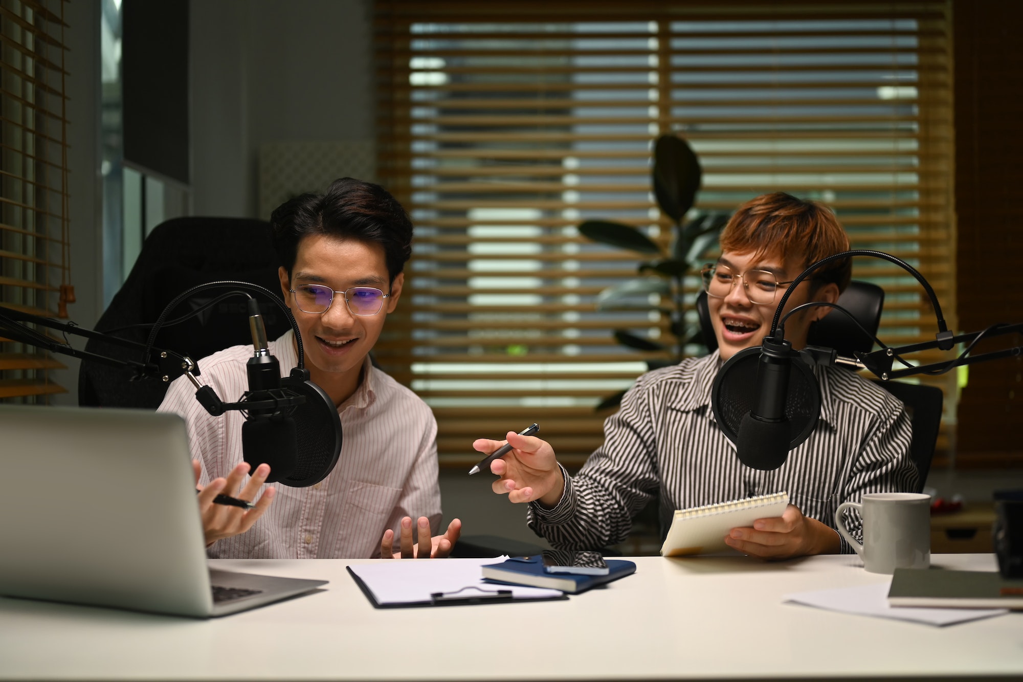 two-smiling-asian-man-podcasters-using-laptop-and-condenser-microphone-to-recording-podcast-.jpg