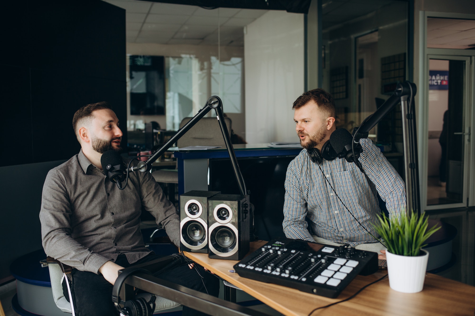 two-smiling-radio-hosts-talking-while-recording-podcast-in-broadcasting-studio.jpg